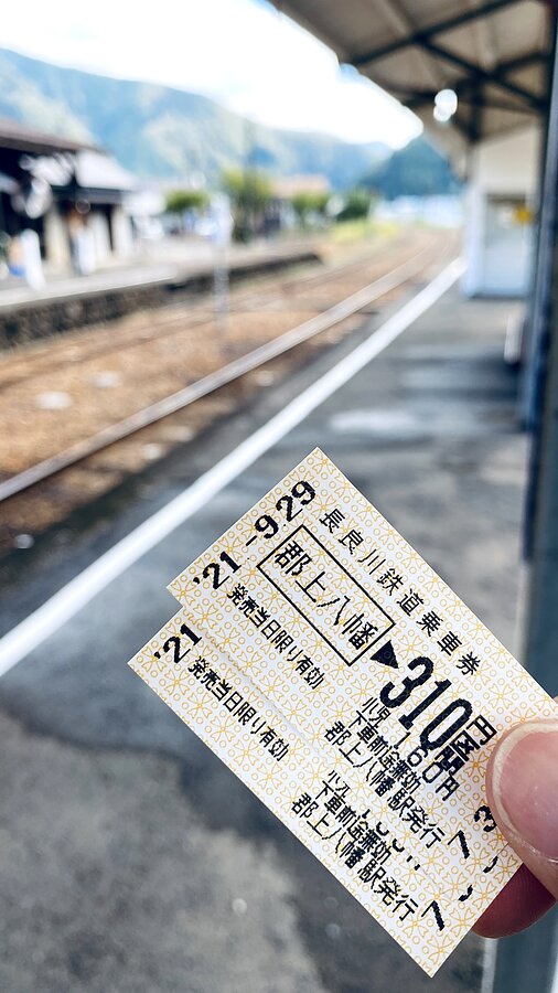 A paper ticket for the Nagaragawa Railway to Gujo Hachiman, held up on the station platform