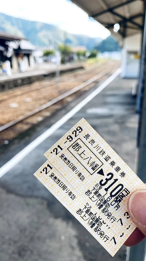 A paper ticket for the Nagaragawa Railway to Gujo Hachiman, held up on the station platform