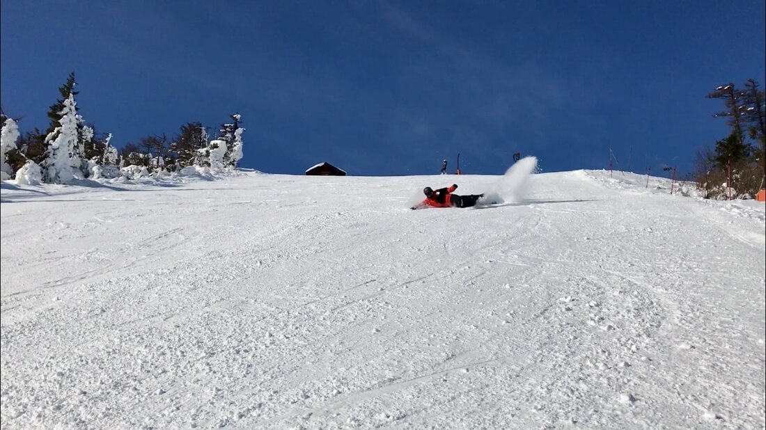 A snowboarder throwing up a spray of powder on a steep run through the trees at one of Gujo's ski resorts